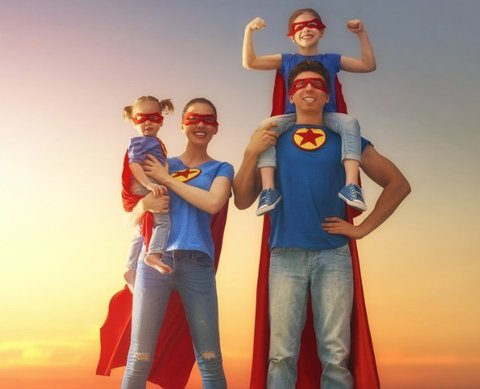 Super hero family, father, mother and two kids standing in front of blue sky with evening dawn