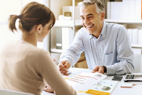 Man talks with woman in business context at desk