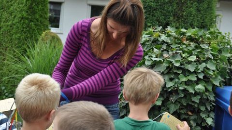 Au-pair taking care lovingly of three blond boys