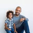 Der glückliche Phil aus München mit seinem lässigen Sohn im Afro-Look sitzen als Partner auf dem Boden