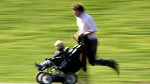 Vater läuft gestresst mit Kinderwagen und seinem Sohn