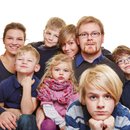 Großfamilie mit 6 Kindern von zwei bis dreizehn Jahren, fünf Jungs und ein zweijähriges Mädchen eng an Mutter und Vater zum Gruppenbild anliegend