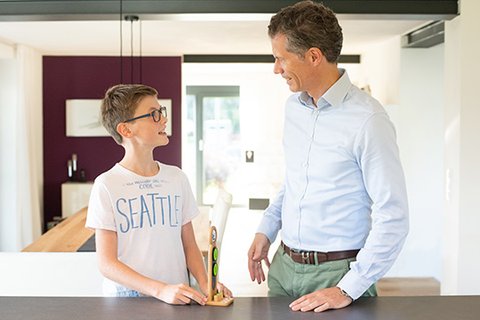 Father gives his twelve year old son sincere feedback, both standing on the kitchen block, with great pride in the boy's eyes and upright posture on both sides