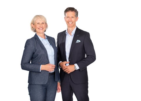 easyfaM founder Heidi Eineder and founder Christian Eineder stand smiling next to each other, both in a blue suit